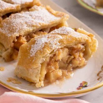 A platter of apple strudel with two pieces cut on the plate.