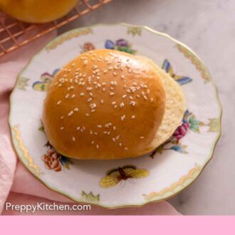 Pinterest graphic of a plate with a brioche bun with sesame seeds on top, sliced in half.
