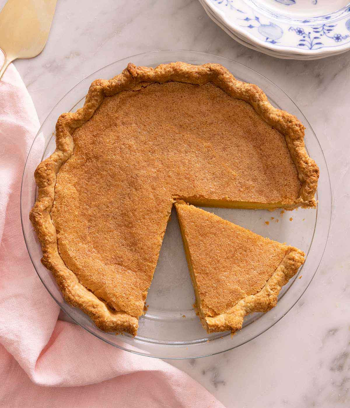 Overhead view of a chess pie in a pie dish with one slice removed and a cut slice in the dish.