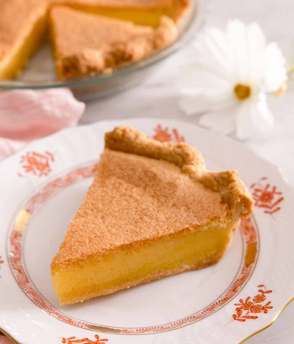 A slice of chess pie on a white plate with orange floral print.
