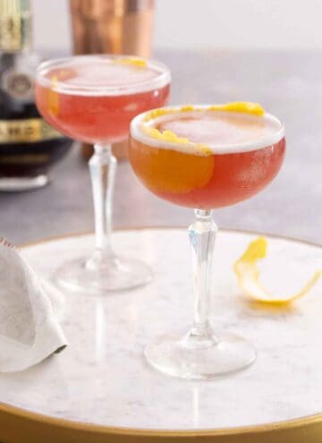 Two glasses of French martini with lemon garnish on a marble surface.