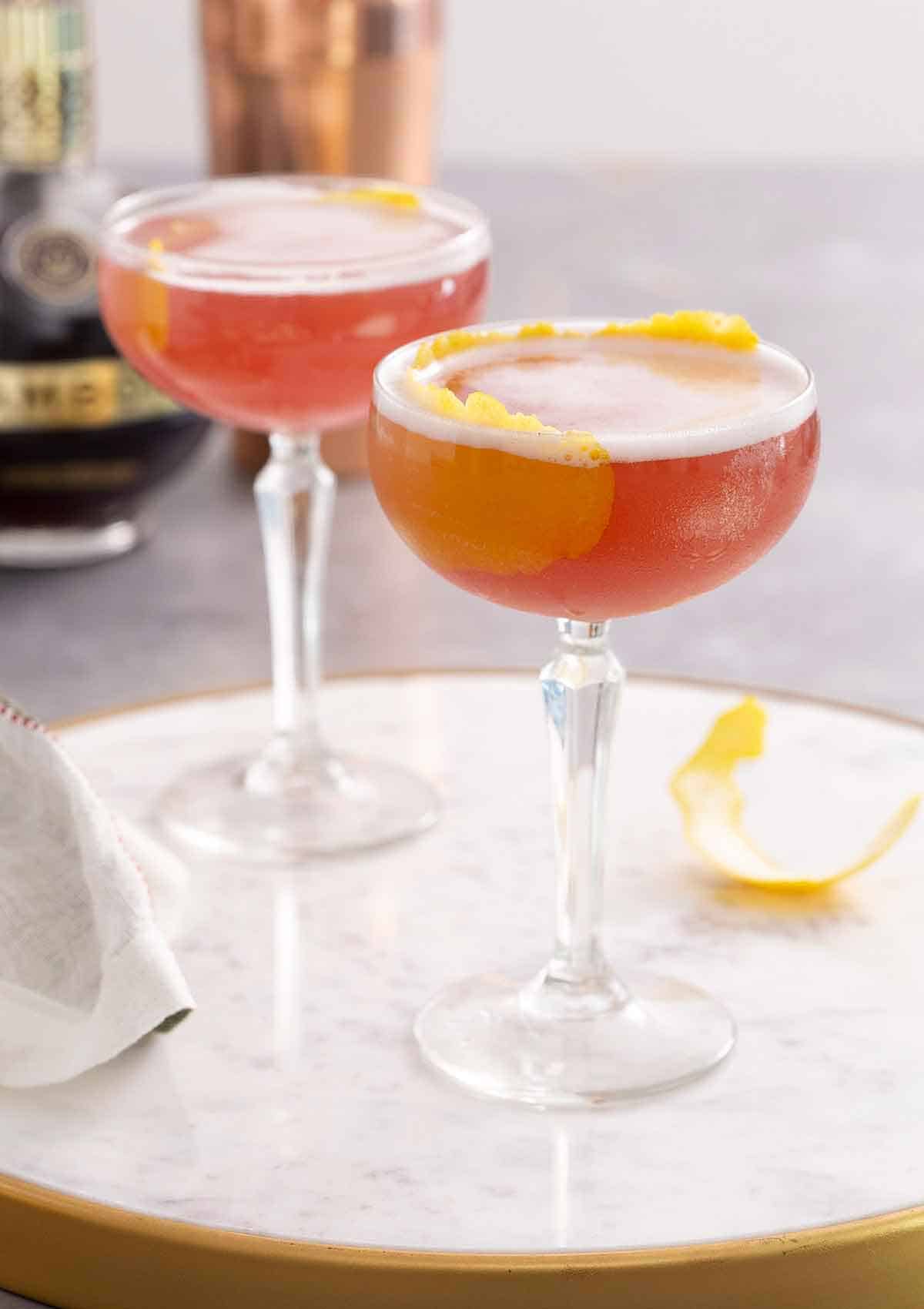 Two glasses of French martini with lemon garnish on a marble surface.