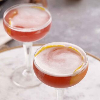 Pinterest graphic of an angled view of two glasses of French martinis, both with lemon peel garnishes.