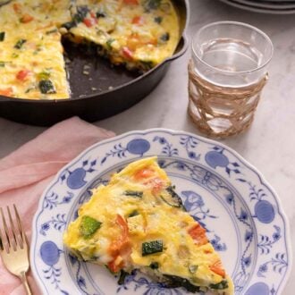 Pinterest graphic of a plate with a slice of frittata with a cast iron with the rest of the frittata in the background.