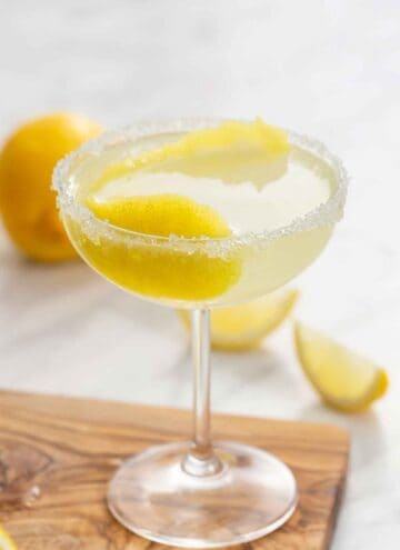 A glass of lemon drop martini with a lemon peel in the glass and a sugared rim.