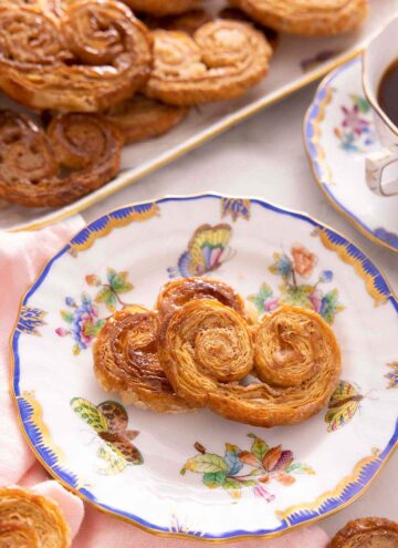 A plate with two palmiers in front of a platter with more.