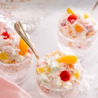 Pinterest graphic of three glass cups of ambrosia salad with a spoon in each.