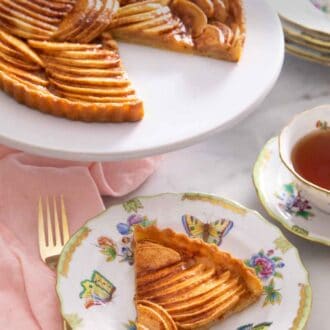 Pinterest graphic of a slice of apple tart in front of a serving stand with the rest of the tart.