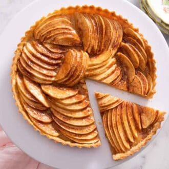 Overhead view of an apple tart with a slice cut and pulled slightly away from it.