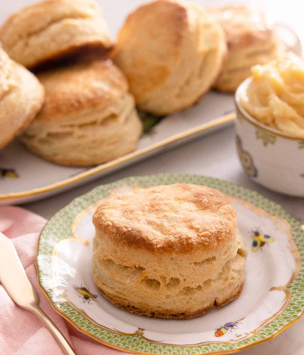 A plate with a biscuit with additional ones in the background on a platter.