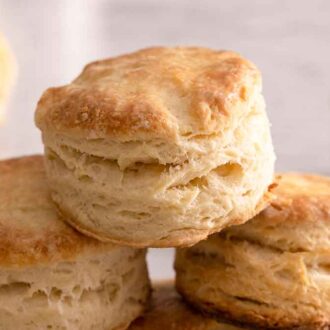 A pyramid of biscuits stacks on top of each other with a bowl of butter in the background.