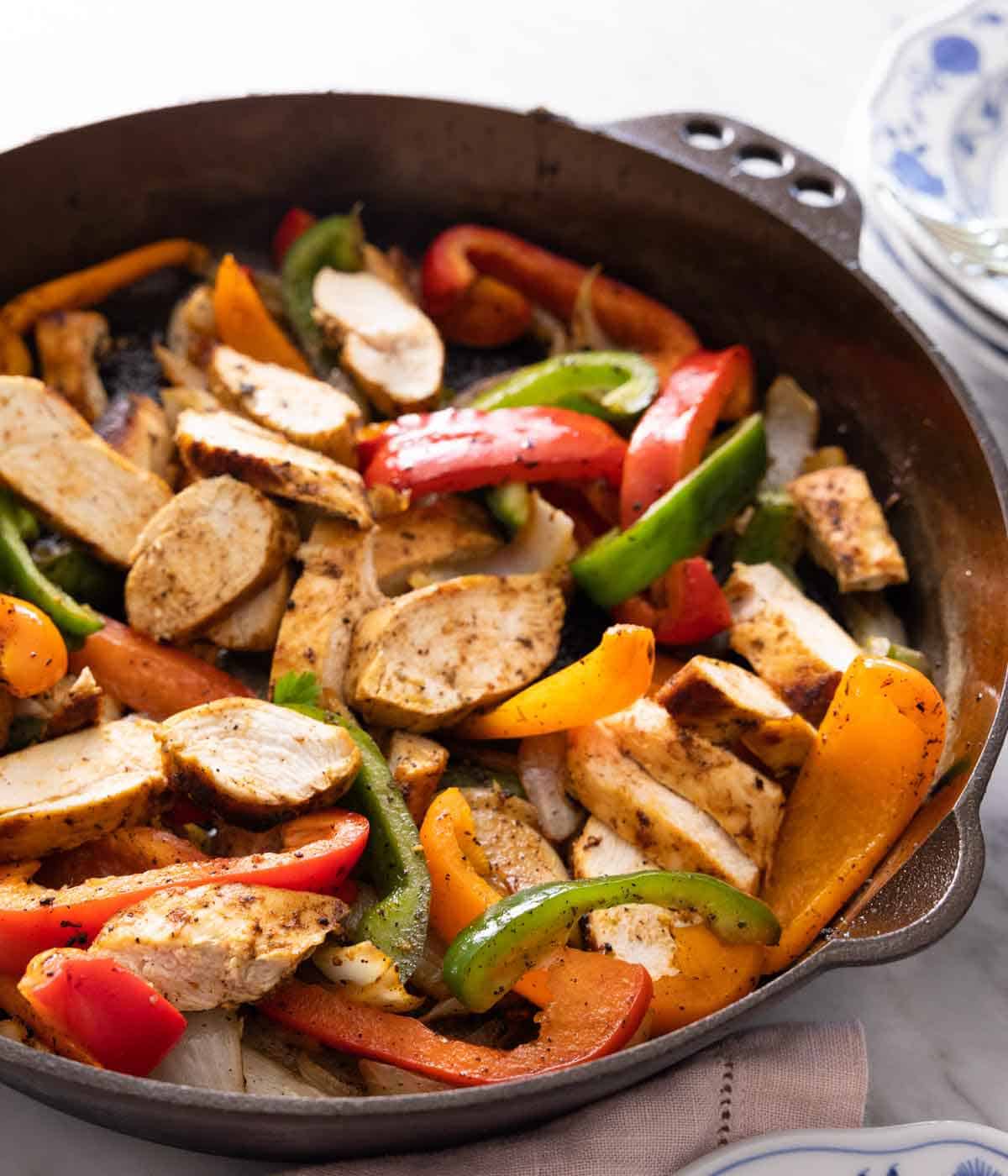 A cast iron skillet with chicken fajitas.