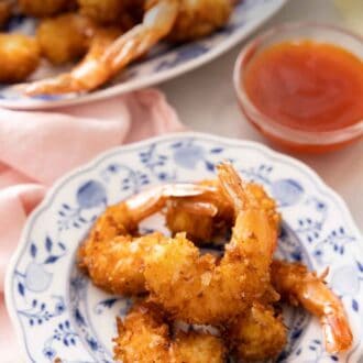 Pinterest graphic of a plate of coconut shrimp with a bowl of dip in the back along with another platter of shrimp.