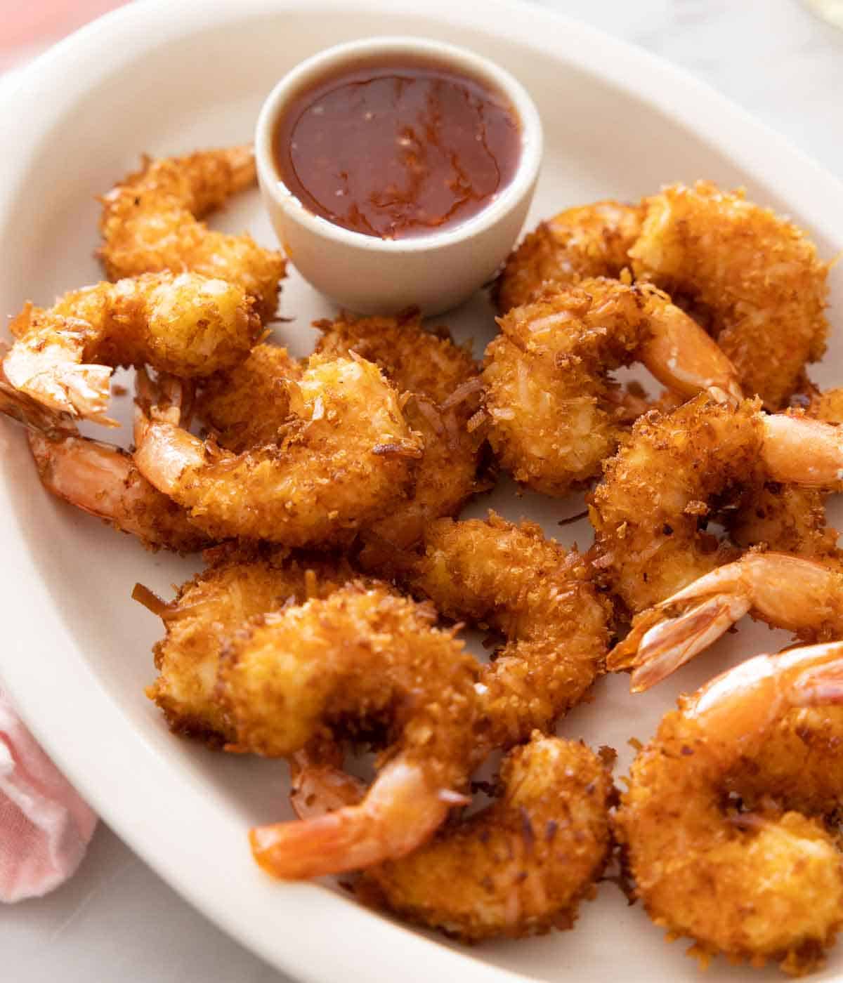 An oval platter with coconut shrimp and a dipping bowl of sauce.