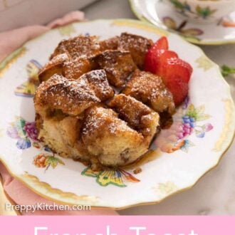 Pinterest graphic of a plate with a serving of French toast casserole with slices strawberries on the side.