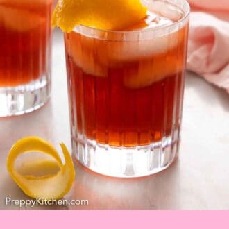 Pinterest graphic of a glass of Negroni with an extra orange peel in front.