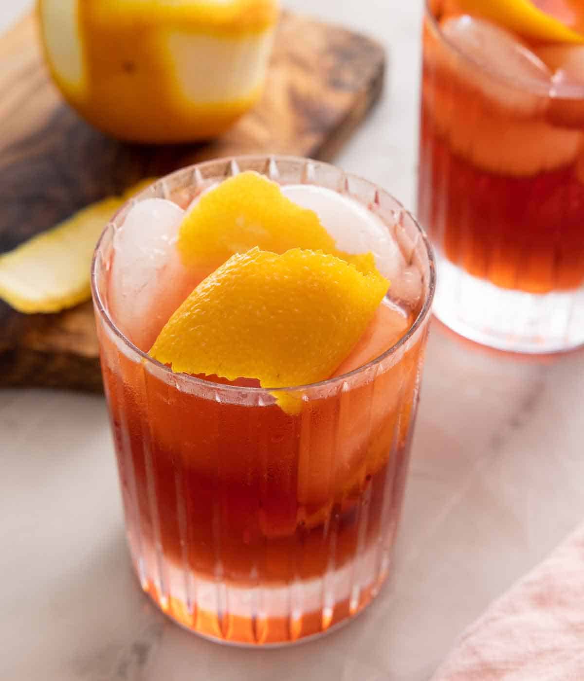 A glass of Negroni with an orange peel garnish.