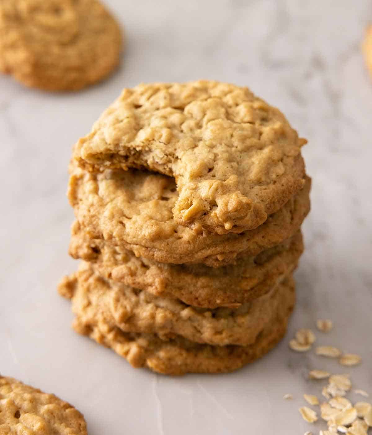 A stack of four peanut butter oatmeal cookies, the top one with a bite taken out.