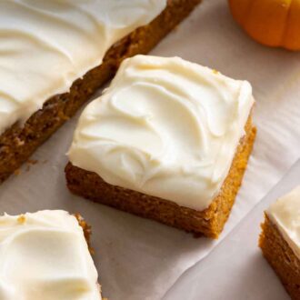 Pinterest graphic a pumpkin cake, cut into squares, with cream cheese on top.