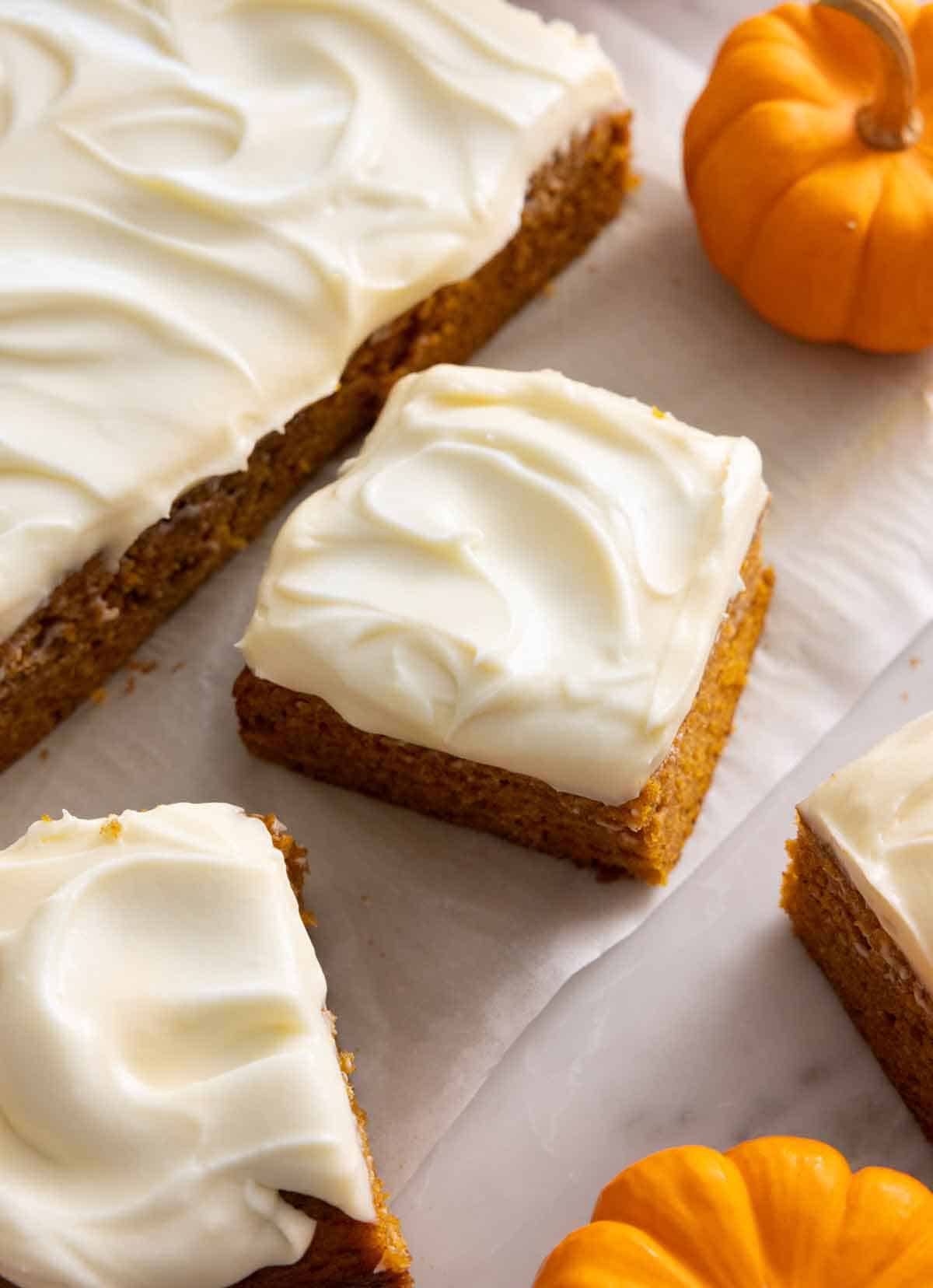 A pumpkin cake with 3 square slices cut and set beside it.