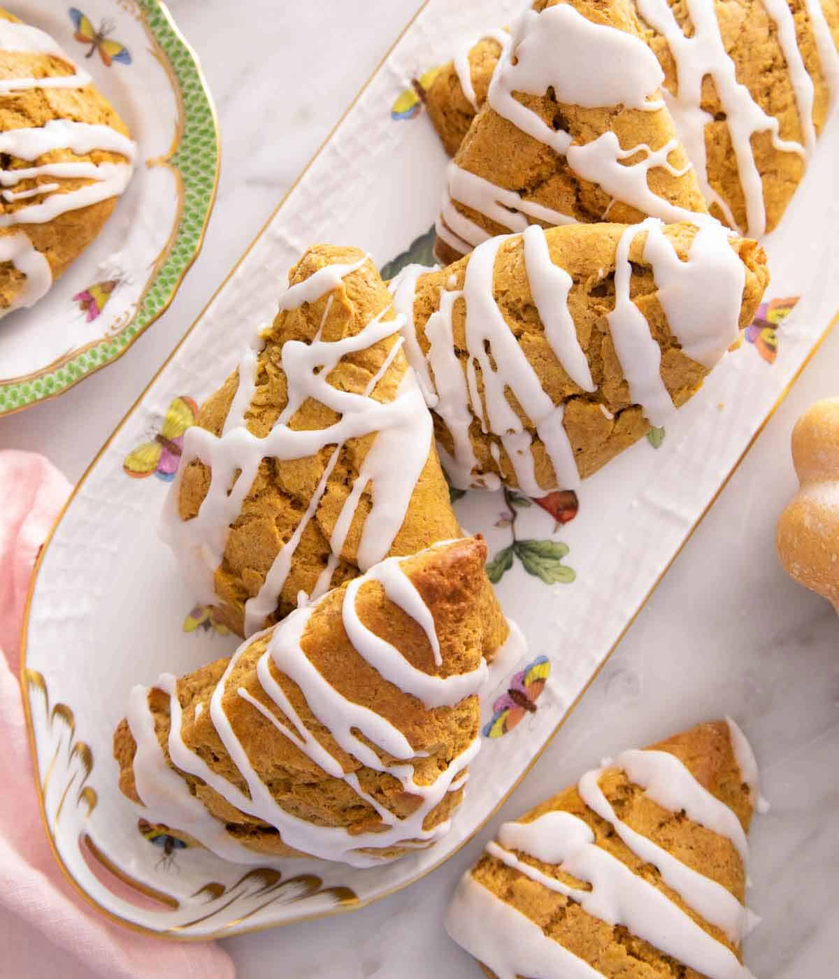 Overhead view of a platter of pumpkin scones with glaze drizzled on top.