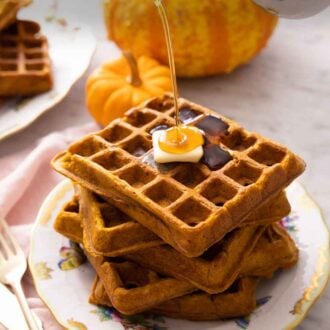 Pinterest graphic of a stack of five pumpkin waffles with a piece of butter on top and syrup poured on top.