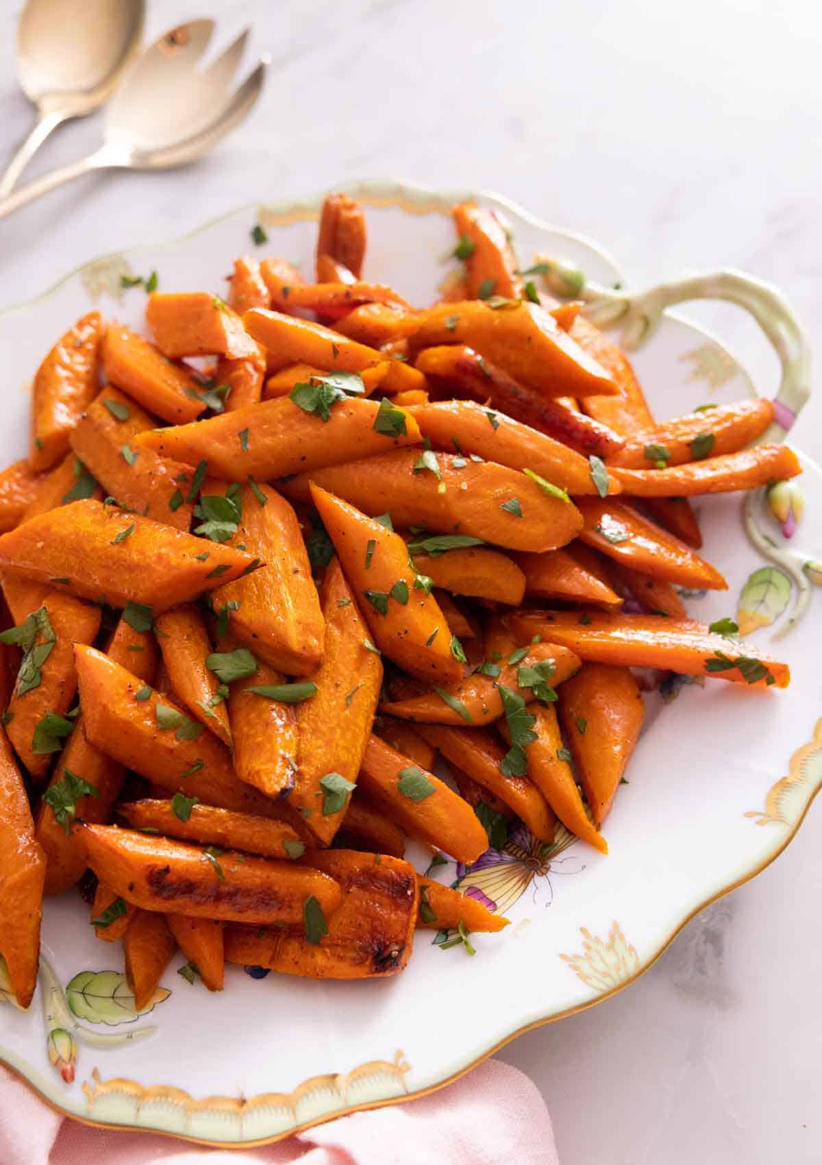 A platter of roasted carrots with parsley on top.