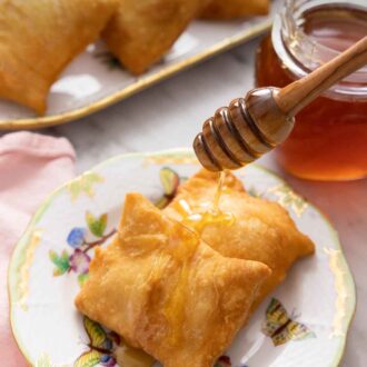 Pinterest graphic of a plate of two sopapillas with honey drizzled over top.