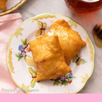 Pinterest graphic of a plate with two sopapillas with honey drizzled on top.