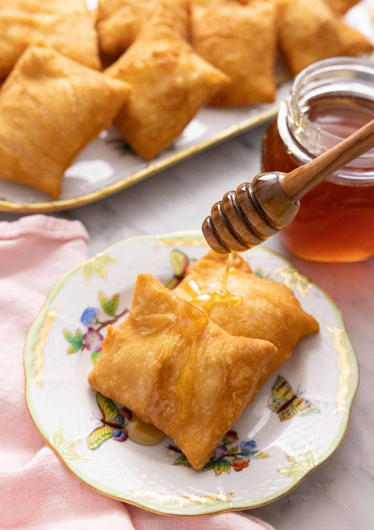 A plate with two sopapillas with honey drizzled over them.