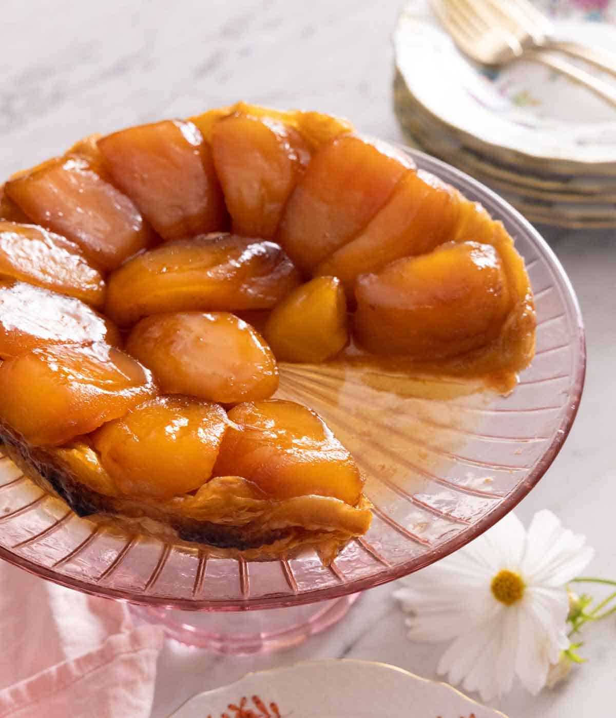 A tarte Tatin with a slice cut out of it on a serving platter.