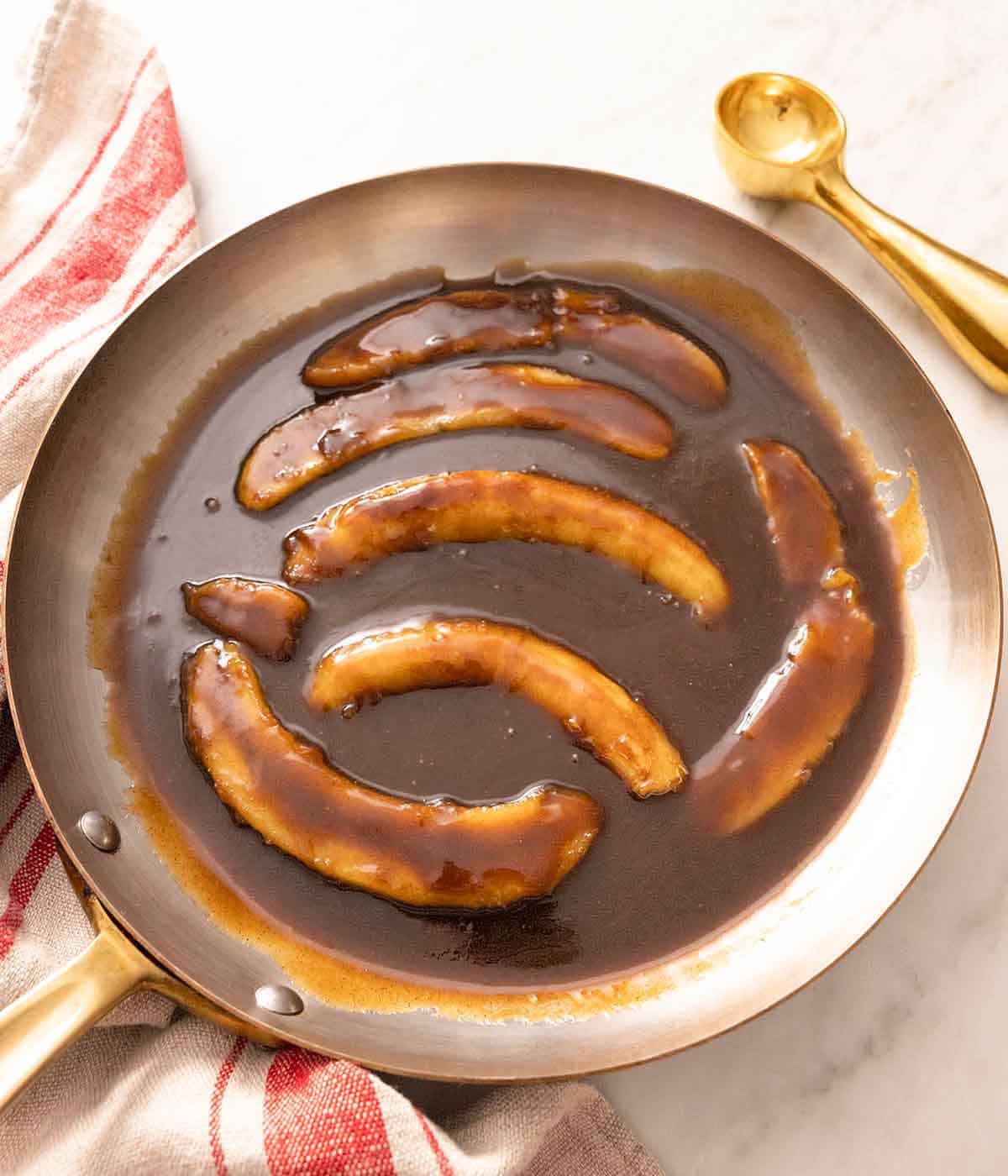 A pan with multiple caramelized bananas with the caramel sauce.