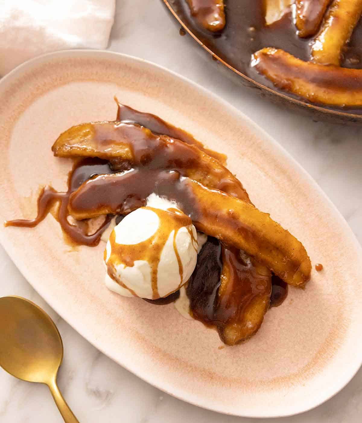 An overhead view of a Banana Foster with a gold spoon beside it.