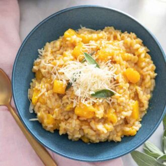 Overhead view of a bowl of butternut squash risotto with a spoon beside it.
