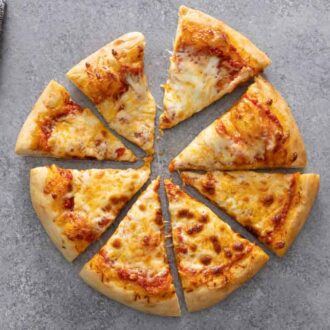 Overhead view of a cheese pizza cut into 8 with one slice pulled out.