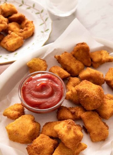 A plate of chicken nuggets with a bowl of ketchup.