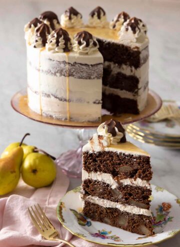 A chocolate pear cake on a cake stand with a slice in front.