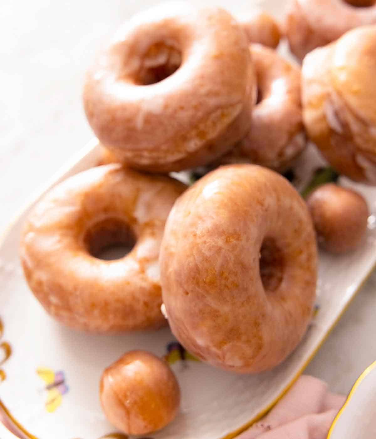 A platter of glazed donuts stacked on top of each other with donut holes.