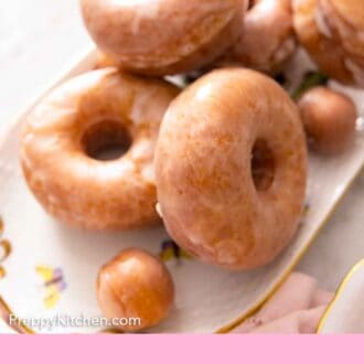 Pinterest graphic of an oval platter of glazed donuts.