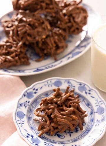 A haystack cookie on a plate with a platter behind it.