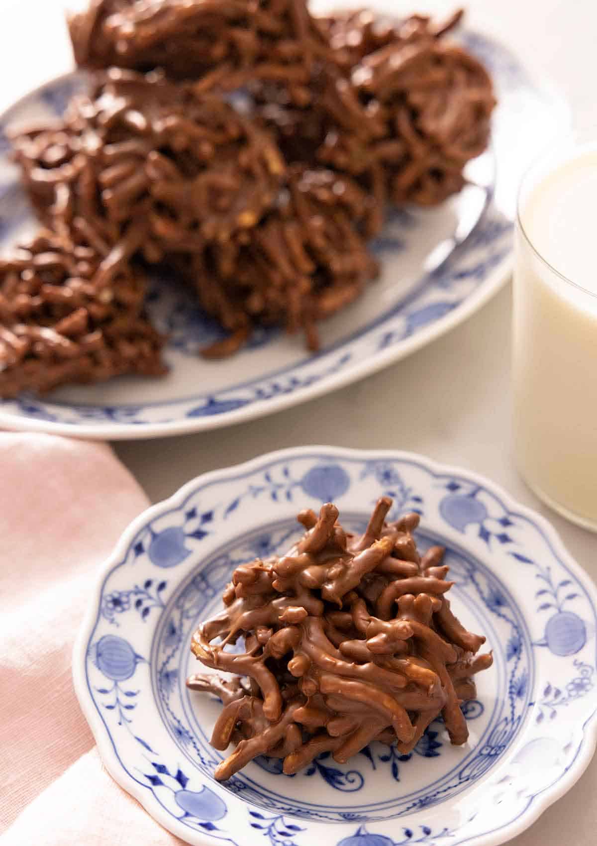 A haystack cookie on a plate with a platter behind it.