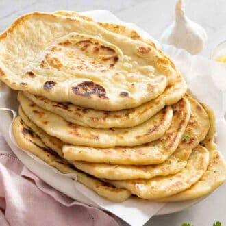 A platter of naan bread by melted butter and garlic and parsley.