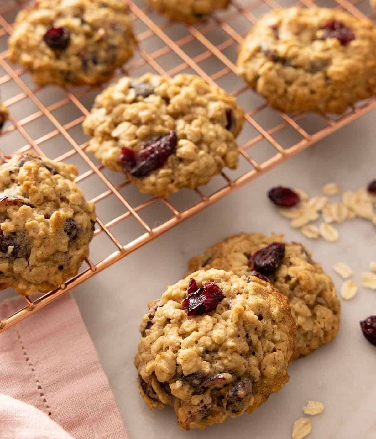 Oatmeal cranberry cookies on a cooling rack and on the counter.
