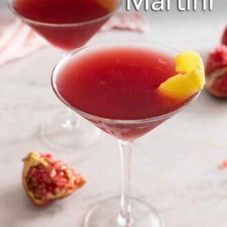 Pinterest graphic of two glasses of pomegranate martinis with lemon peel garnishes.