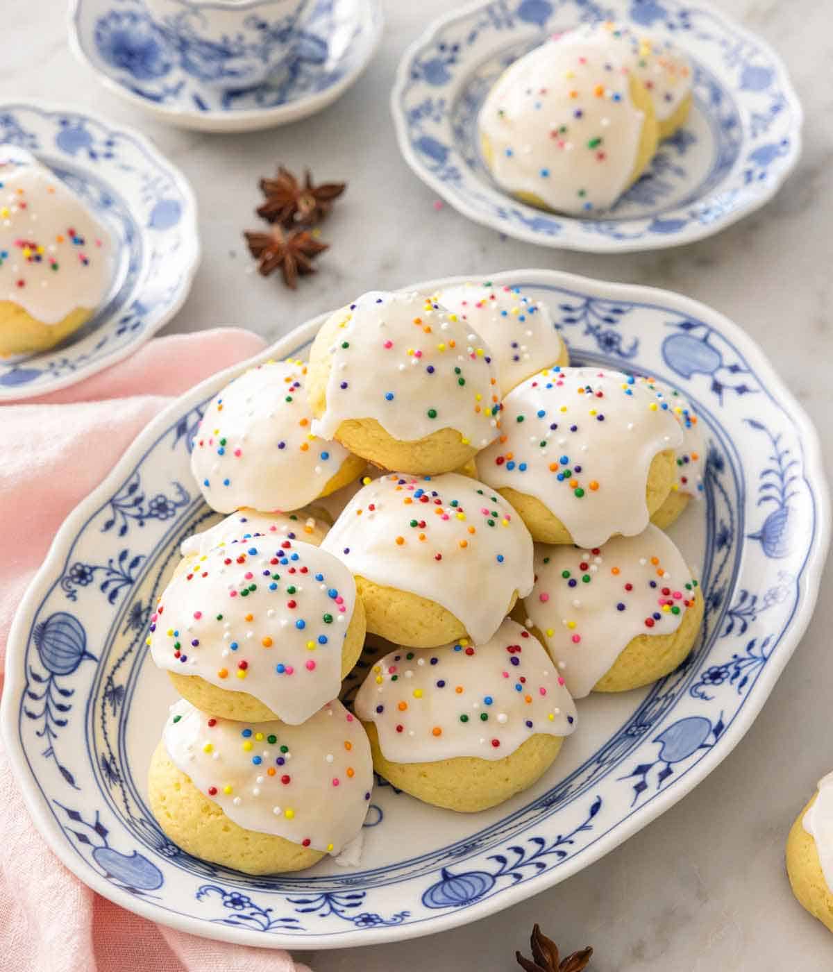A platter of anise cookies with a few on a serving plate behind it.