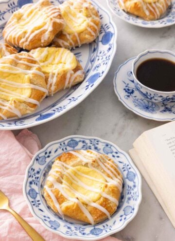 A plate with cheese danish in front of a platter with more.