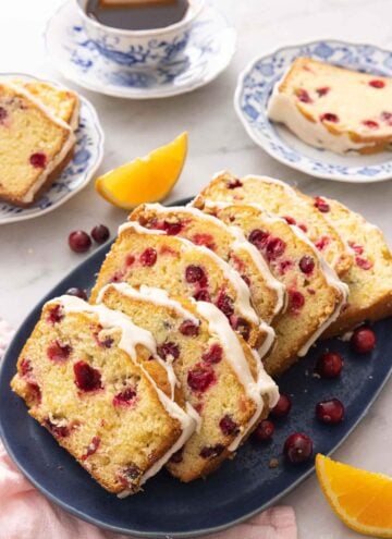 A platter with sliced cranberry orange bread with fresh fruit around it.