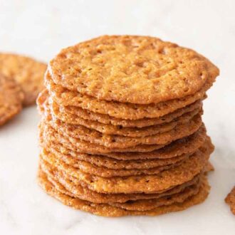 A stack of lace cookies with a couple scattered around.