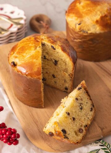 A loaf of panettone with a slice cut out on a cutting board.