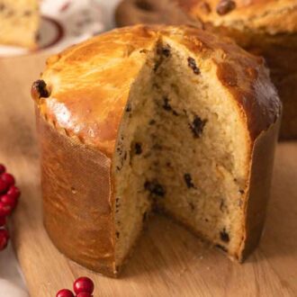 A cut Italian Christmas bread on a cutting board in front of another loaf.